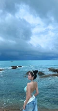 浪漫海边礁石上，身着蓝色肩带泳装加牛仔裤的优雅身形女生写真照片