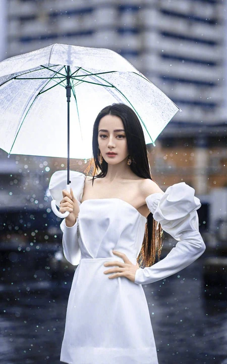 迪丽热巴纯白连衣裙穿着，手拿雨伞，雨中漫步优雅动人青春写真图片