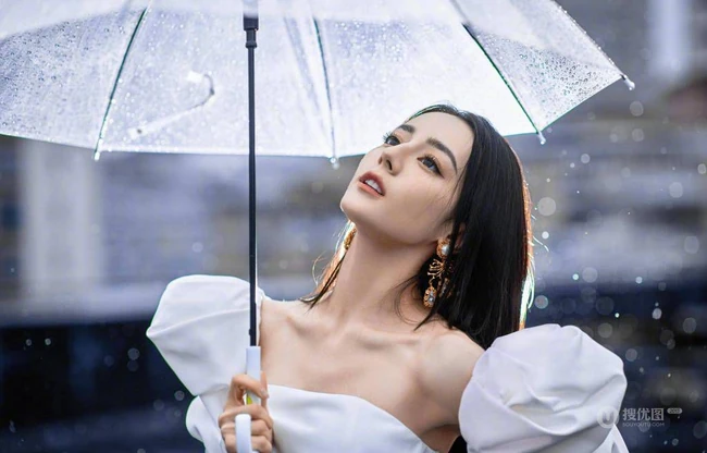 迪丽热巴纯白连衣裙穿着，手拿雨伞，雨中漫步优雅动人青春写真图片