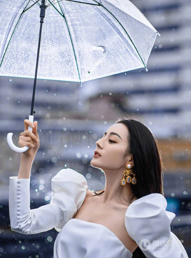 迪丽热巴纯白连衣裙穿着，手拿雨伞，雨中漫步优雅动人青春写真图片