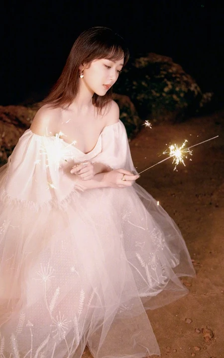 杨紫气质V领白裙着身，手拿烟花，夜晚海边浪漫动人写真照