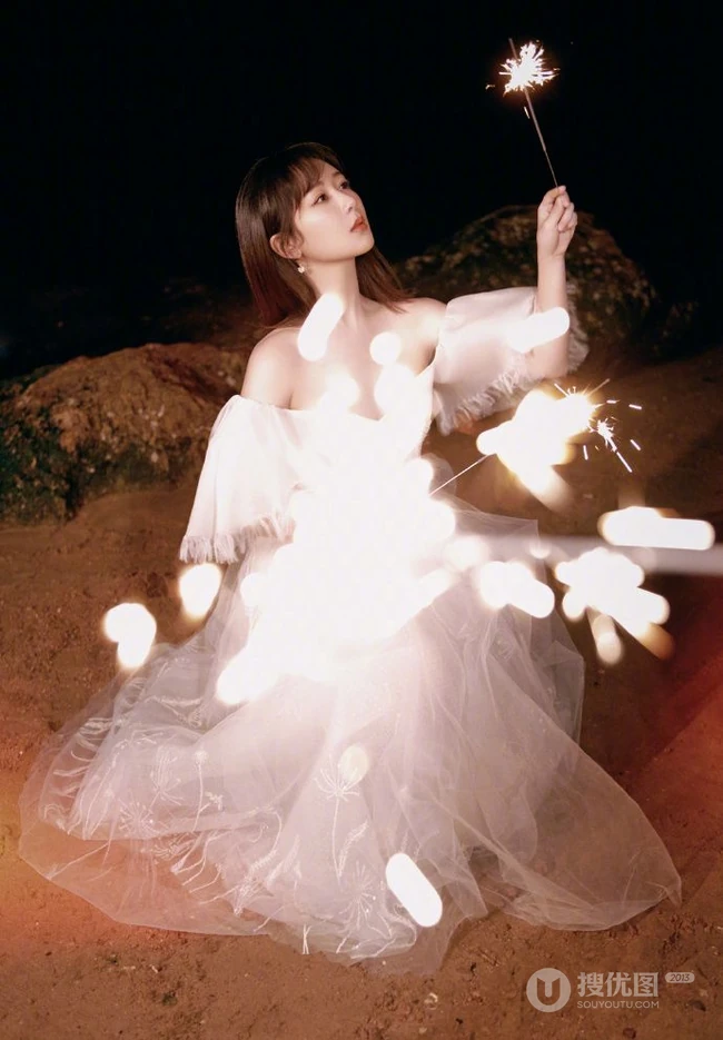 杨紫气质V领白裙着身，手拿烟花，夜晚海边浪漫动人写真照