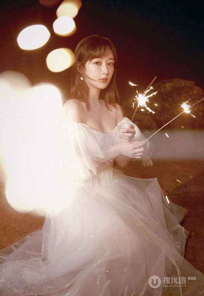 杨紫气质V领白裙着身，手拿烟花，夜晚海边浪漫动人写真照