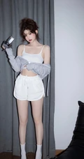 娇俏动人，表情可爱的白色肩带礼裙衣短裤少女手拿相机居家写真照
