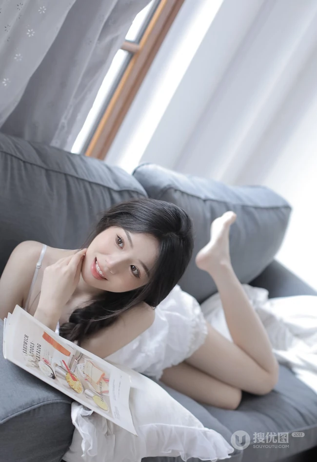 沙发上看画报的甜美可人少女白色肩带居家裙装穿搭高清室内美照
