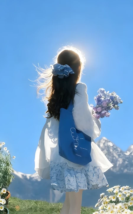 蓝天雪山下手持花束的女生清新治愈背影