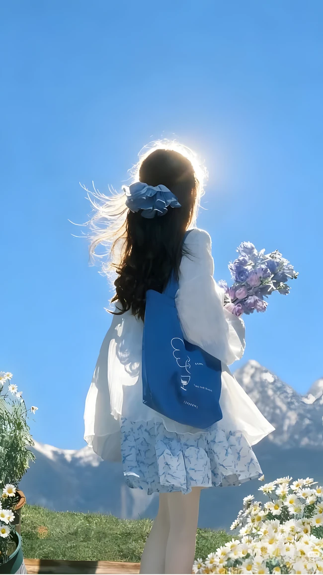 蓝天雪山下手持花束的女生清新治愈背影