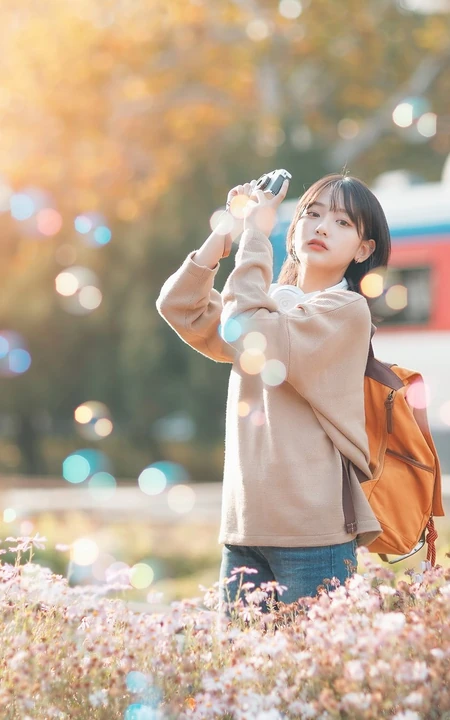 秋日花海间举相机的清新少女户外写真