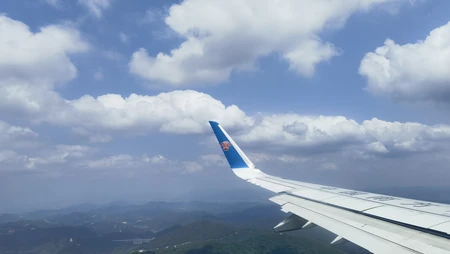 南航航班舷窗边高空蓝天白云山峦景致