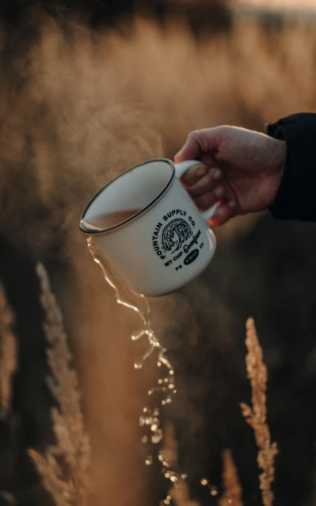 暖调夕阳郊外手持搪瓷杯倾洒清水唯美画面